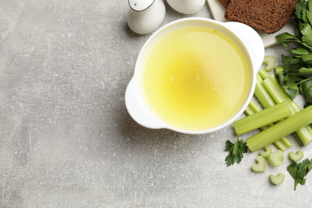 Tasty chicken bouillon served on grey table, flat lay. Space for textの写真素材