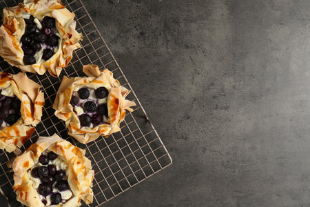 Delicious puff pastries with blueberries on gray textured table, top view. Space for textの写真素材