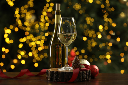 Glass and bottle of white wine with Christmas decor on wooden table against blurred lights. Bokeh effectの写真素材