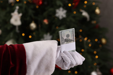 Santa Claus with dollar banknotes near Christmas tree indoors, closeupの写真素材