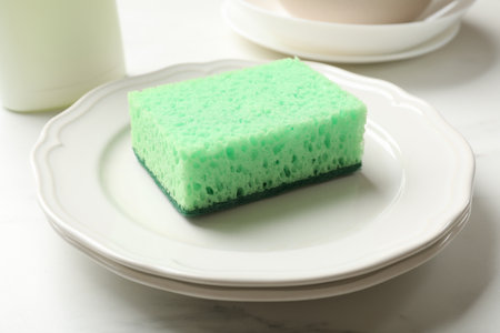 Green sponge and plates on white table, closeupの写真素材