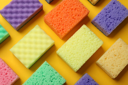 Colorful sponges on yellow background, flat lay. Cleaning toolの写真素材