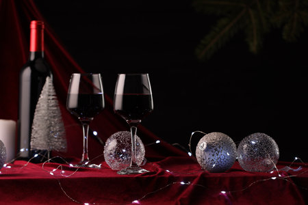 Red wine, Christmas lights and ornaments on table. Space for textの写真素材