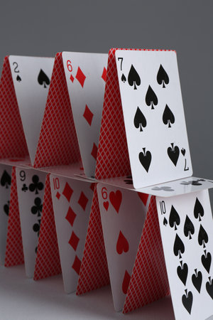 House of playing cards on gray background, closeup