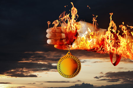 Woman holding gold medal in her flaming hand against darkened sky, closeupの写真素材