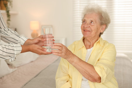 Senior woman getting glass of water indoorsの写真素材