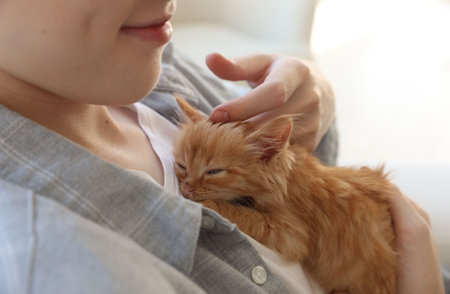 Teenage boy with his cute ginger kitten indoors, closeupの写真素材