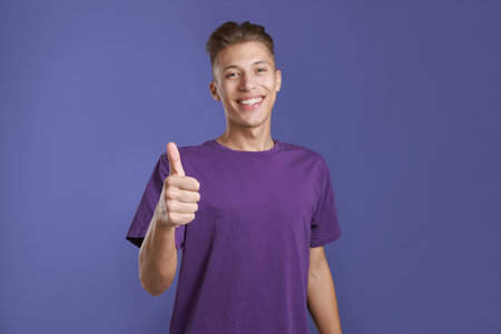 Happy man showing thumbs up on purple background. Like gesture