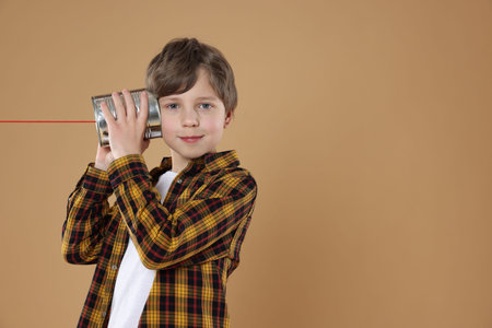 Person using tin can telephone on beige background. Space for text