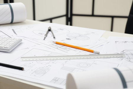 Different engineering drawings and tools on table in officeの写真素材