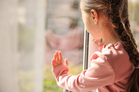 Orphanage concept. Sad girl near window indoorsの写真素材