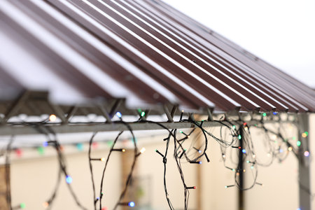 Roof of house decorated with Christmas lights outdoors, closeup