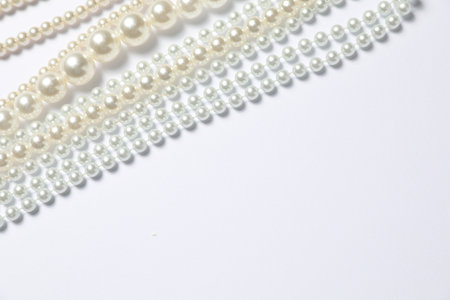 Beautiful pearl necklaces on white background, flat lay. Space for textの写真素材
