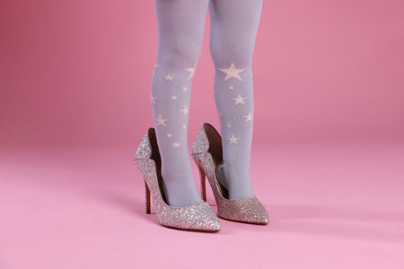 Child wearing tights and heels on pink background, closeupの写真素材