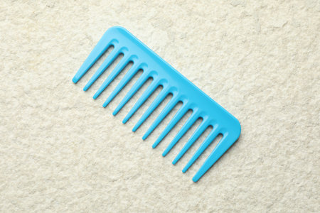 One light blue plastic comb on beige background, top viewの写真素材