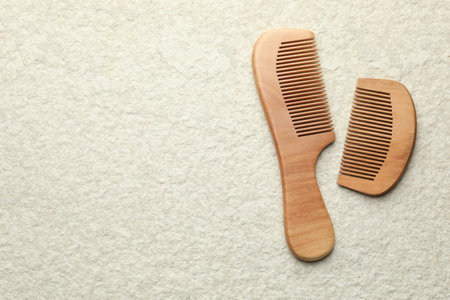 Different wooden hair combs on beige background, top view. Space for text