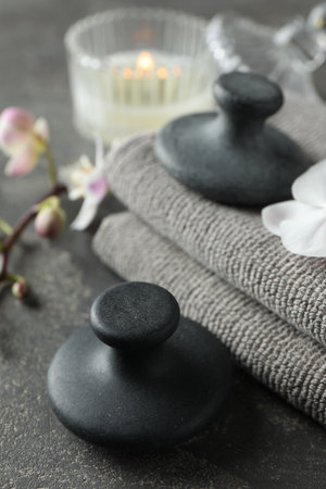 Spa stones, towels, orchid branch and candle on gray table, closeupの写真素材