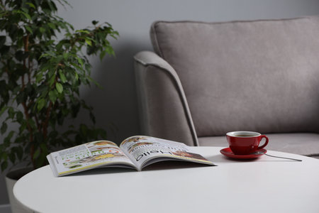 Cup of drink and magazine on stylish coffee table indoors, closeupの写真素材