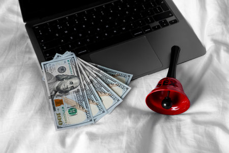 Laptop, dollar banknotes and bell on linesの写真素材