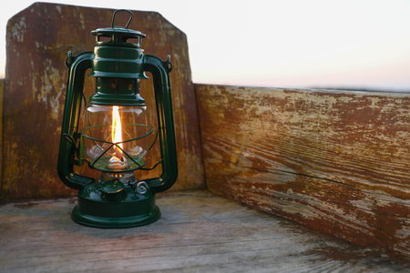 Vintage kerosene lamp in wooden boat near river at sunsetの写真素材
