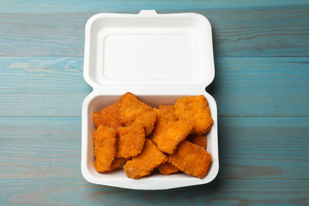 Chicken nuggets in takeaway container on blue wooden table, top viewの写真素材