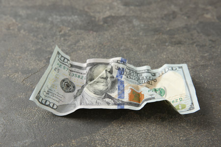 One crumpled dollar banknote on gray table, closeup