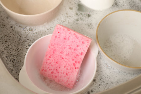Pink sponge, dishes and foam in sink, closeupの写真素材