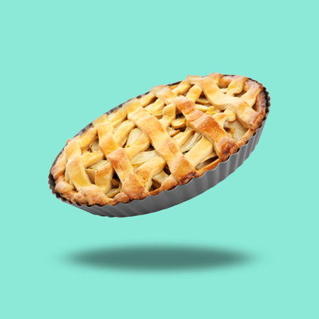 Delicious traditional apple pie in air on turquoise backgroundの写真素材
