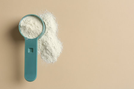 Protein powder and scoop on beige background, top view. Space for textの写真素材