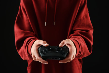 Teenage boy playing video game with controller on black background, closeupの写真素材