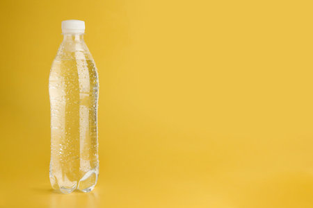 Plastic bottle of water on yellow background, space for textの写真素材