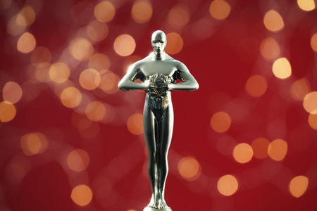 Golden trophy in shape of human figure on red background with blurred lightsの写真素材