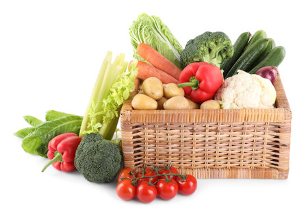 Different ripe vegetables in wicker box isolated on whiteの写真素材