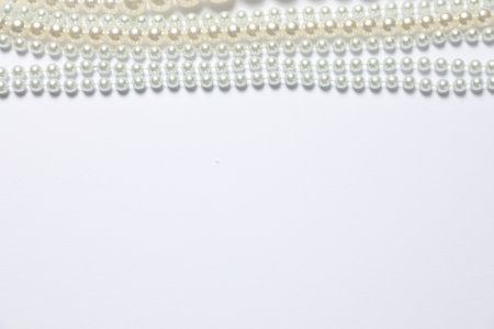 Beautiful pearl necklaces on white background, flat lay. Space for textの写真素材