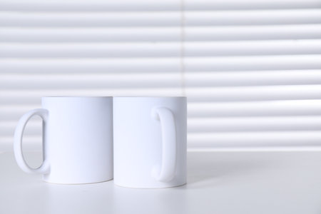 Blank ceramic mugs on white table. Mockup for designの写真素材