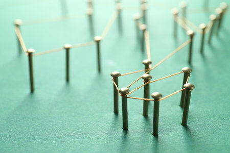 Network connection. Nails linked together by thread on green background, closeup