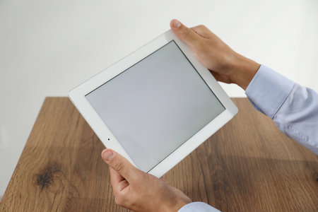 Businessman using tablet at wooden table, closeup. Modern technologyの写真素材