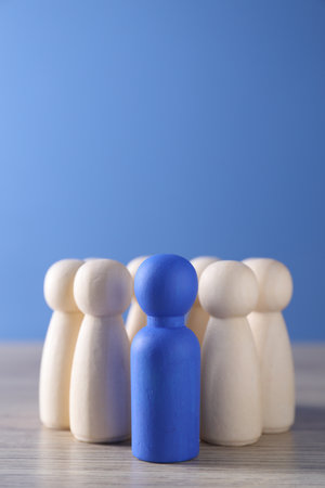 Human resources concept. Blue figure among wooden ones on table, closeup. Space for textの写真素材