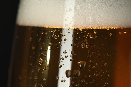 Glass of beer with condensation drops on black background, macro viewの写真素材