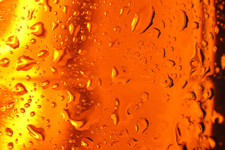 Water drops on orange glass surface, macro view
