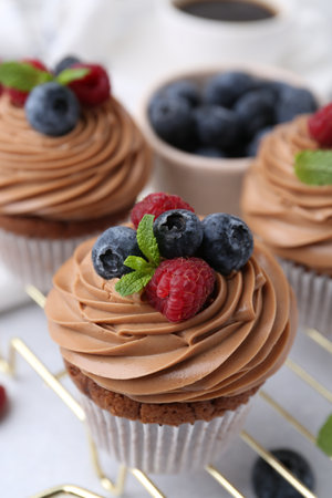 Tasty cupcakes with chocolate cream and berries on white table, closeupの写真素材