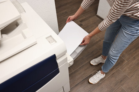 Woman using modern printer indoors, closeup. Printing houseの写真素材