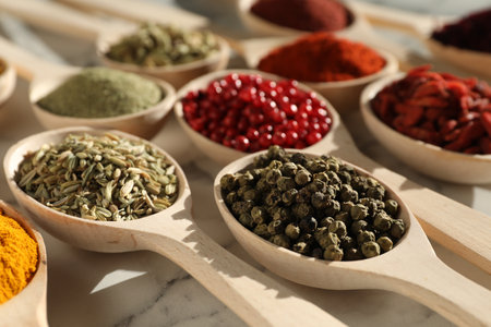 Different aromatic spices in spoons on white marble table, closeupの写真素材