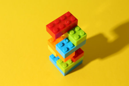 Construction toy. Figure made with building bricks on yellow backgroundの写真素材