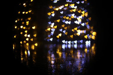 Romantic decor. Blurred view of heart shaped lights on black background, bokeh effectの写真素材