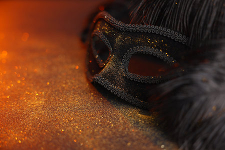Beautiful carnival mask and black feathers on glitter background, closeup. Space for textの写真素材