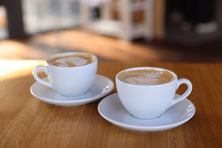 Cups of aromatic coffee on wooden table in cafe, closeup