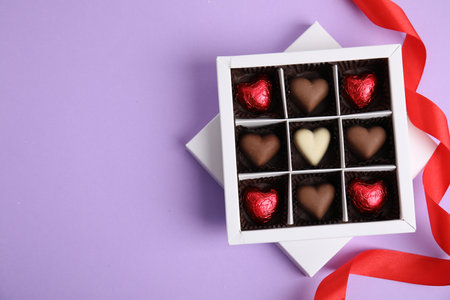 Tasty heart shaped chocolate candies on violet background, flat lay with space for text. Happy Valentine's dayの写真素材
