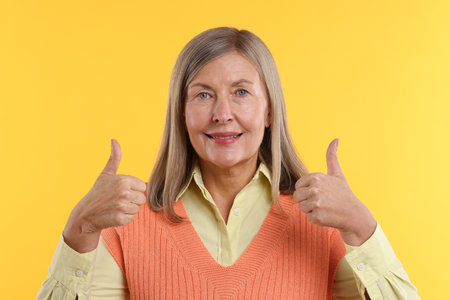 Person showing thumbs up on yellow background