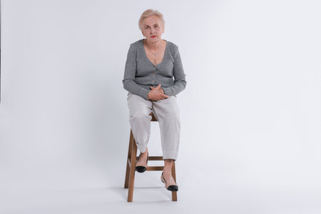 Senior person sitting on chair against white backgroundの写真素材